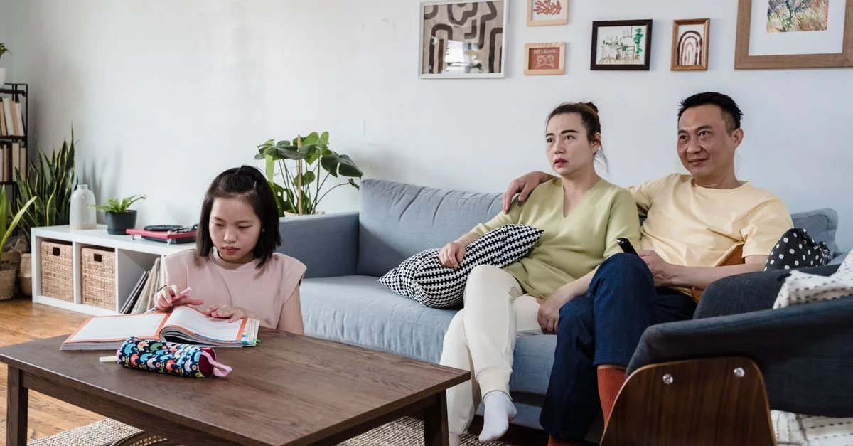 Famille profitant de moments ensemble dans un salon élégant, enfant lisant pendant que les parents se détendent.